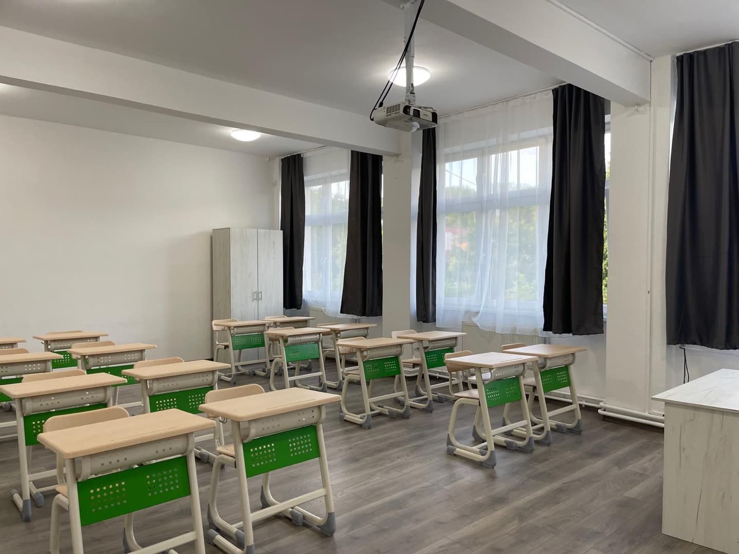 Sala de clasă amenajată la Școala „Andrei Șaguna” din Turda: bănci noi cu panouri verzi, podea laminată și videoproiector montat în tavan