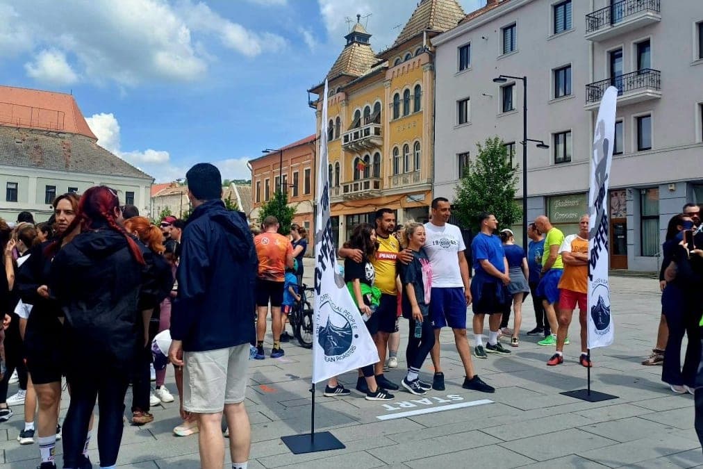 Startul crosului „Alergăm pentru Patric” în Piața Republicii din Turda, cu steagurile Turda Coffee Run și zeci de participanți adunați la linia de plecare