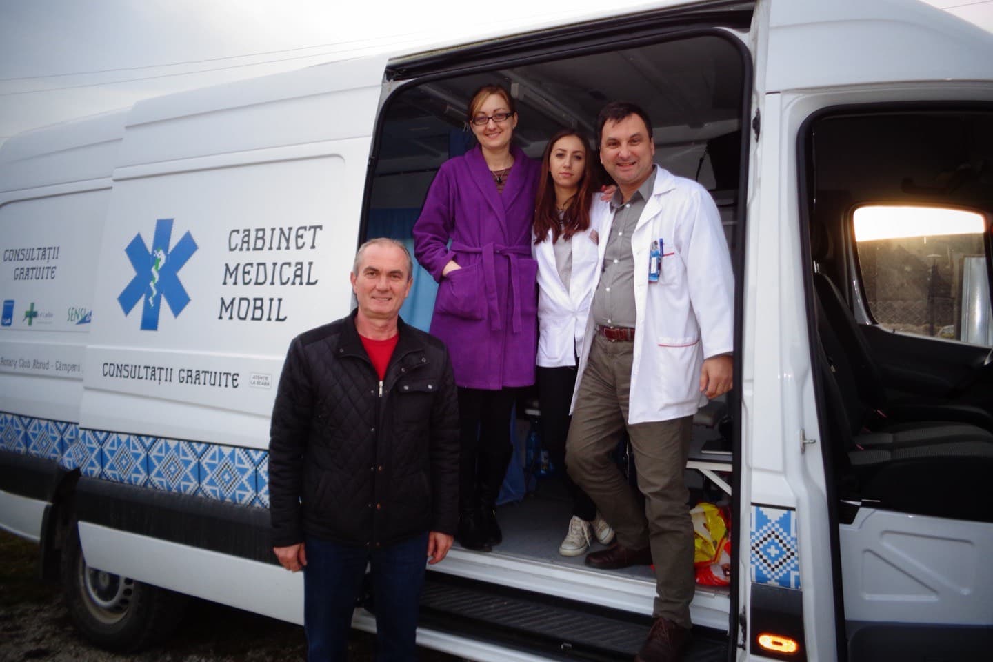 Autoutilitara „Cabinet medical mobil — consultații gratuite”, împrumutată de la Rotary Club Abrud-Câmpeni, cu doi medici în halate albe în ușa din spate